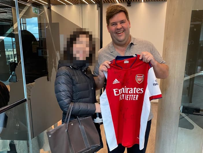 アーセナルのサイン入りユニフォームを持ったCEOのティムさん